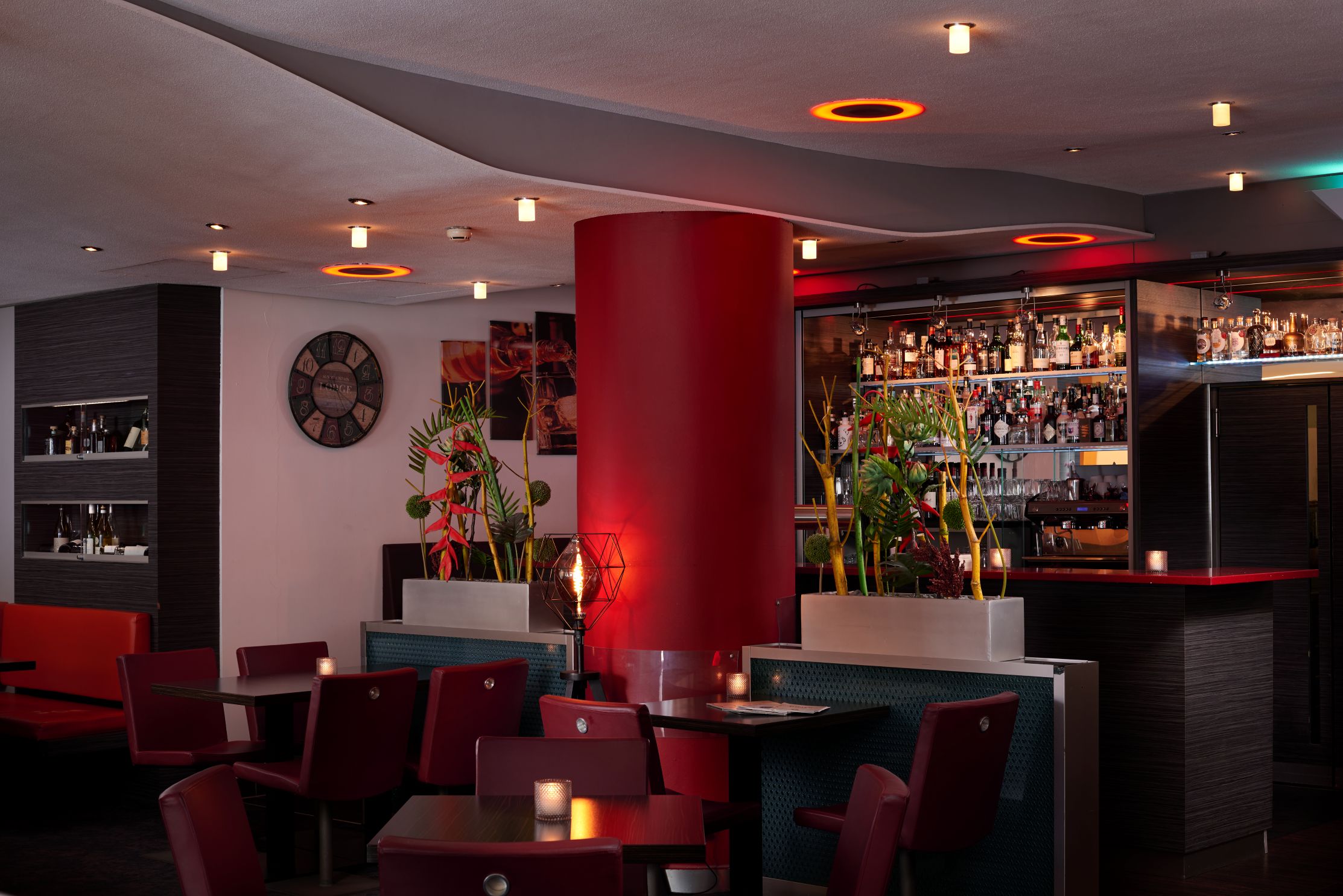 Moderne Bar mit roten Sesseln und Säule warme Beleuchtung Pflanzen und Flaschenregale